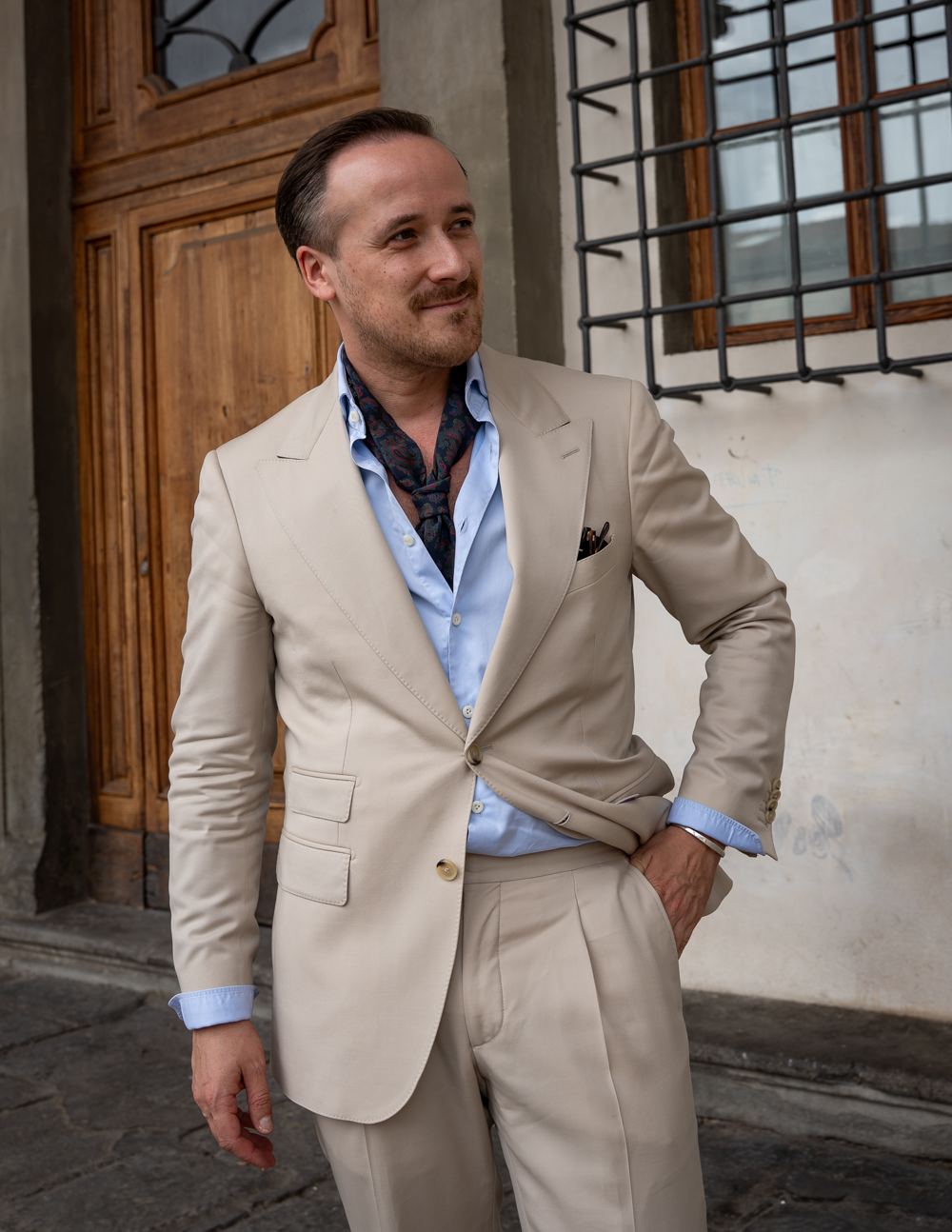 Joe Laschet im hellen Maßanzug vor einer Holztür in Florenz